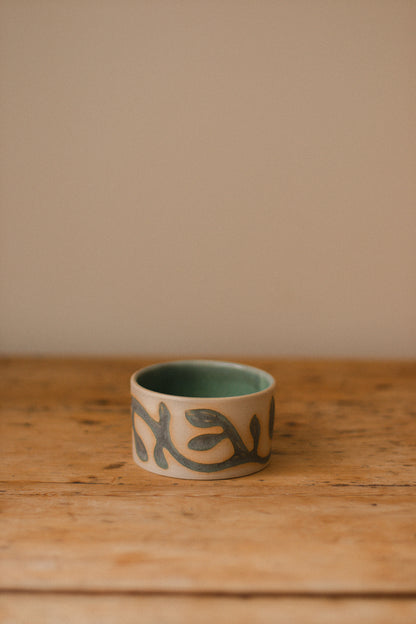 Small ceramic piece with a hand-carved vine pattern filled with matte blue glaze.
