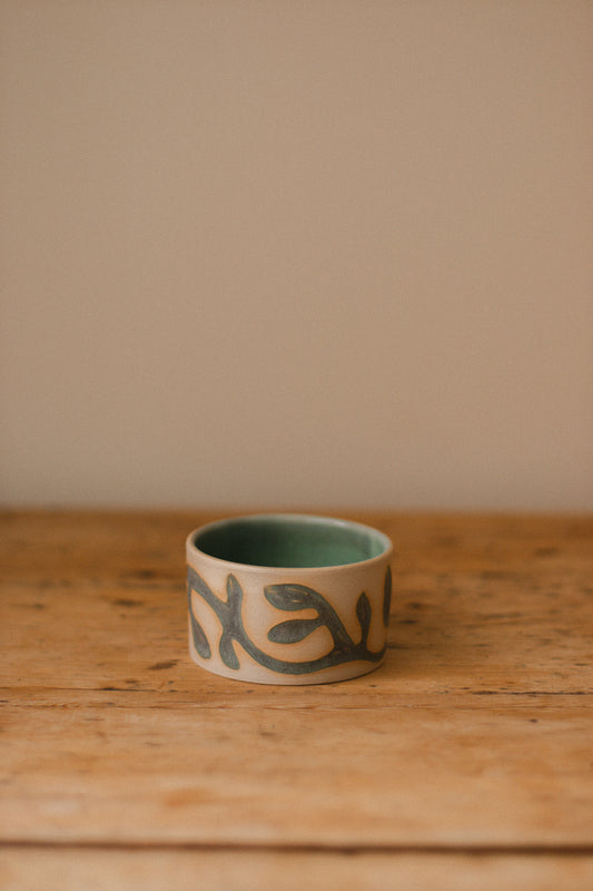 Small ceramic piece with a hand-carved vine pattern filled with matte blue glaze.